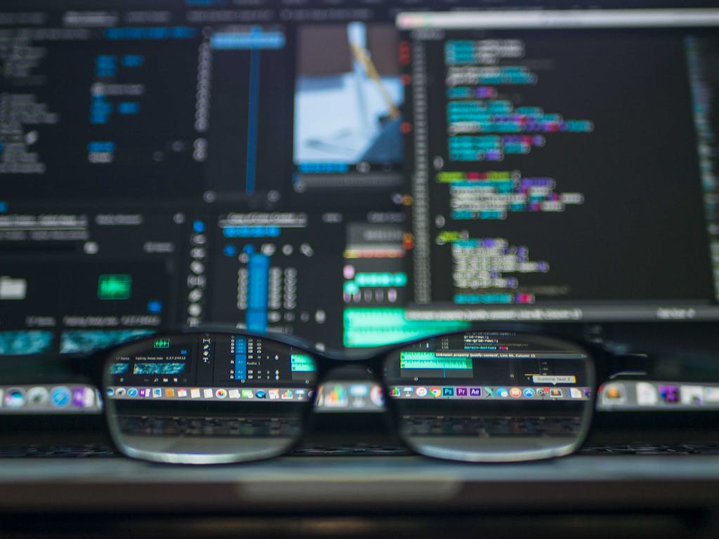 Glasses in front of a colourful computer screen with website code on